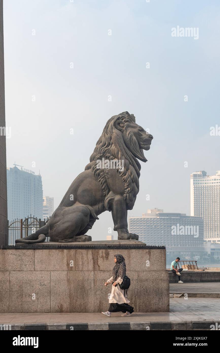 Cairo, Egitto. 1 luglio 2024. Una donna cammina davanti a uno dei famosi leoni di bronzo che sorvegliano il ponte Qasr El Nil sul fiume Nilo nel centro del Cairo. (Foto di John Wreford/SOPA Images/Sipa USA) credito: SIPA USA/Alamy Live News Foto Stock