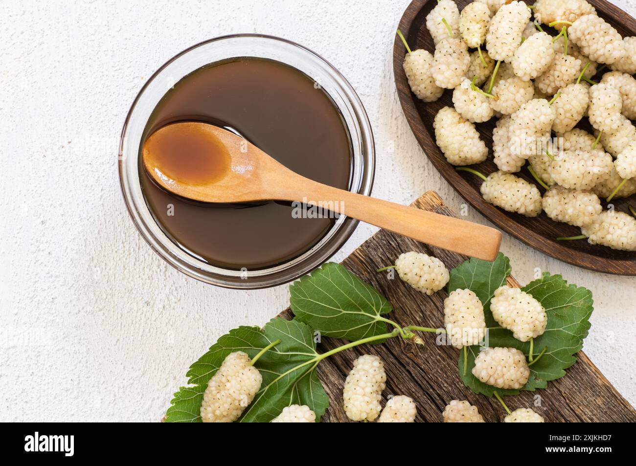 Melassa di gelso bianco in una ciotola di vetro e cucchiaio di legno con gelso fresco, cibo sano Foto Stock