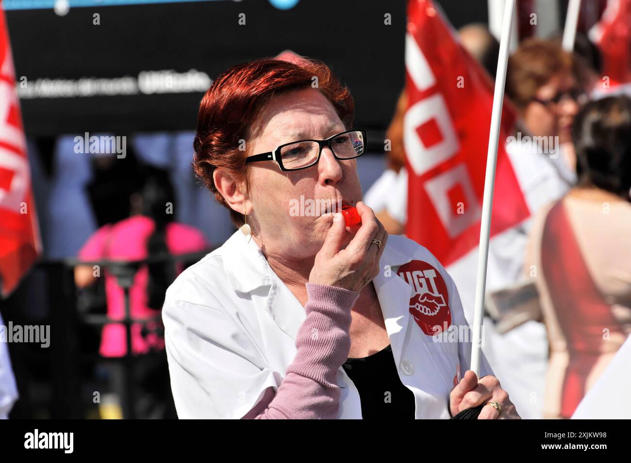 Madrid, Spagna, Europa, Una donna mangia una mela e partecipa a una dimostrazione con bandiere rosse UGT Foto Stock