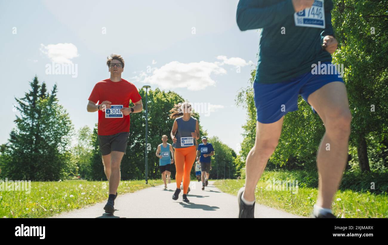 Ritratto di un gruppo di persone che partecipano insieme a una maratona e corrono attraverso un sentiero del parco. Jogger che danno il meglio per raggiungere il traguardo in una gara amichevole Foto Stock