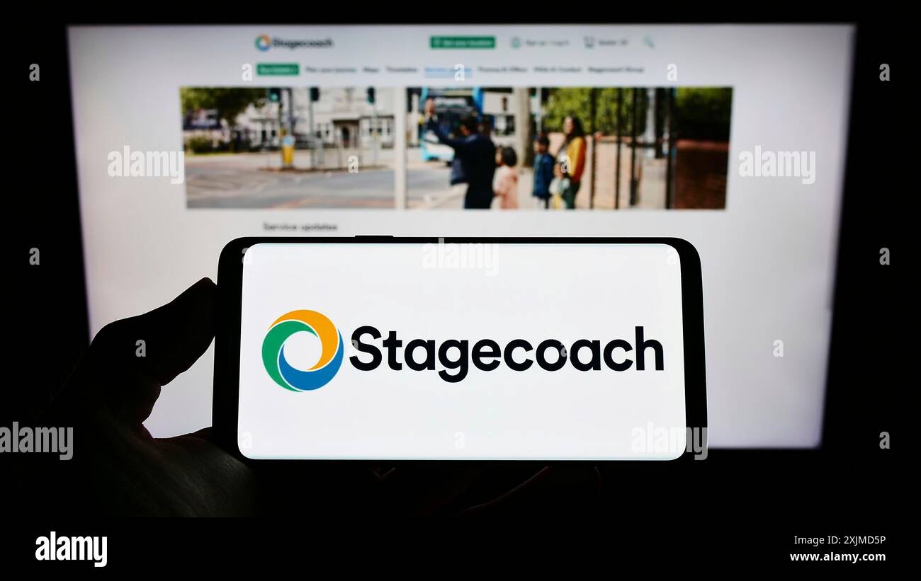 Stoccarda, Germania, 05-26-2022: Persona che detiene il cellulare con il logo della società britannica di autobus Stagecoach Group plc sullo schermo davanti all'azienda Foto Stock