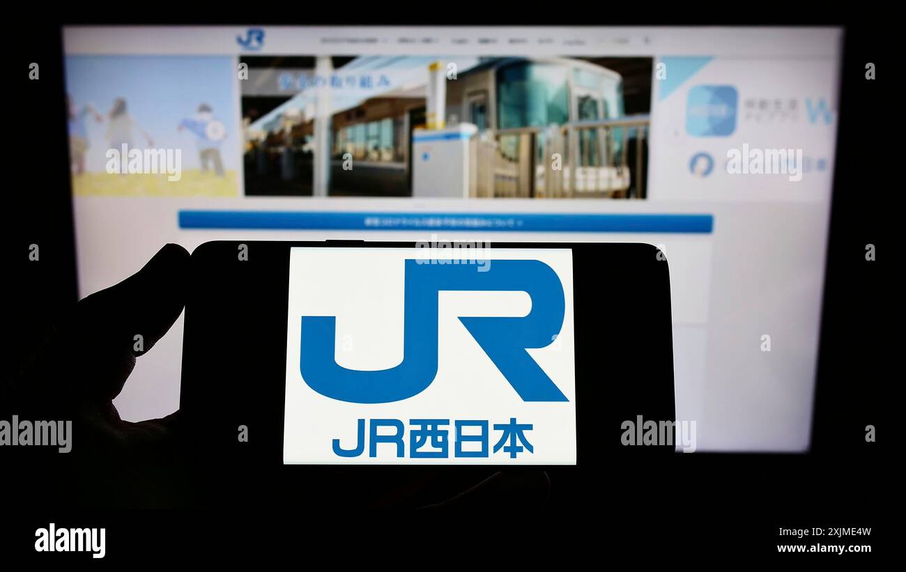 Stoccarda, Germania, 06-06-2022: Persona in possesso di smartphone con logo della compagnia giapponese West Japan Railway (JR) sullo schermo davanti al sito web. Concentrati Foto Stock