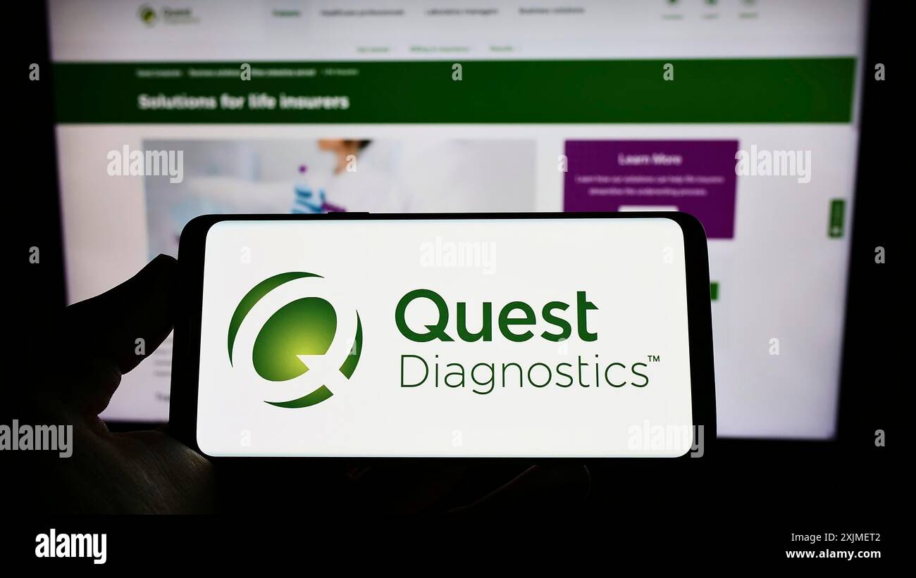 Stuttgart, Germania, 06-12-2022: Persona che possiede uno smartphone con il logo della società di laboratorio statunitense quest Diagnostics Inc. Sullo schermo davanti al sito Web. Foto Stock