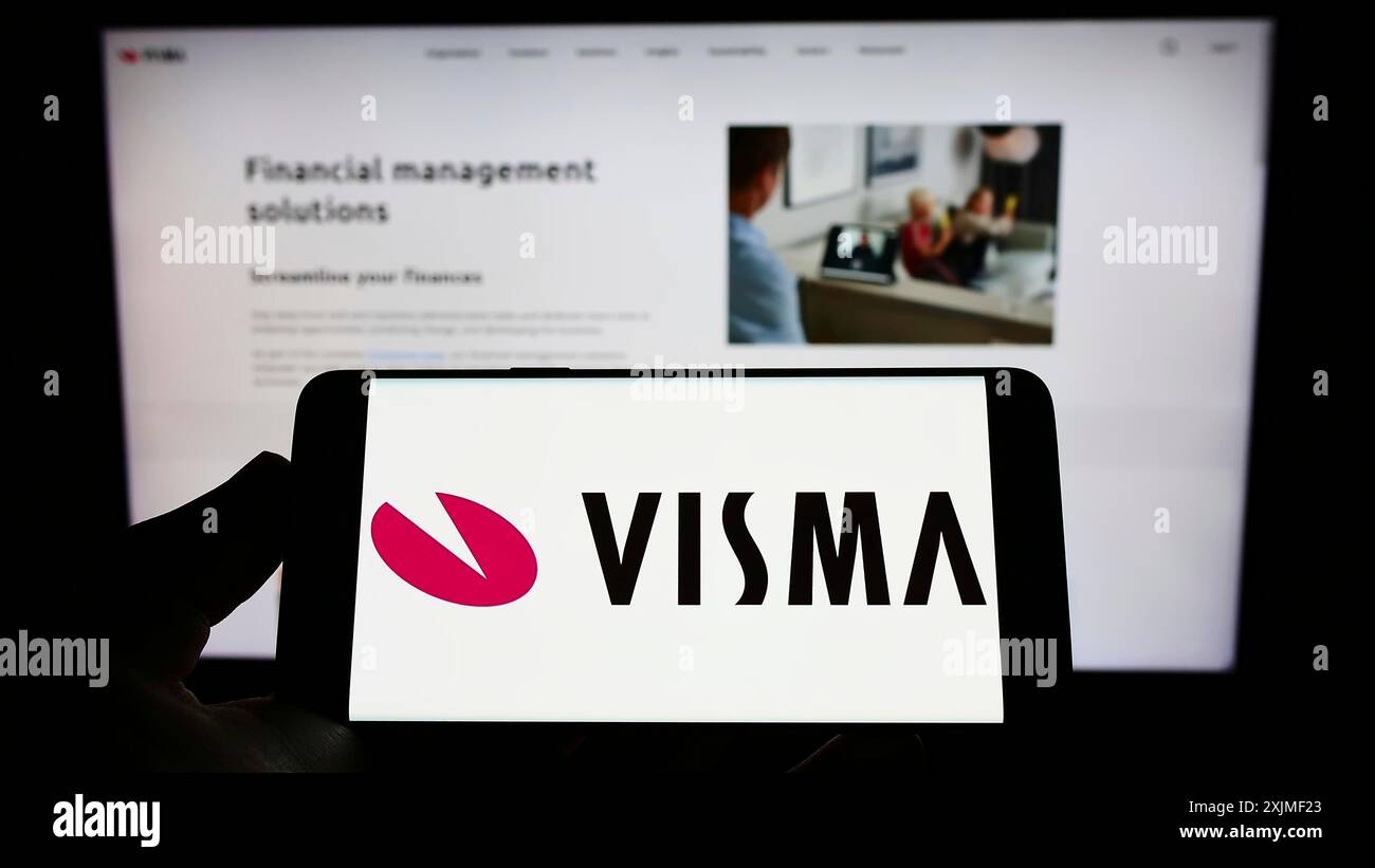 Stoccarda, Germania, 06-12-2022: Persona che detiene il cellulare con il logo della società norvegese di software Visma COME sullo schermo di fronte alla pagina web aziendale. Foto Stock