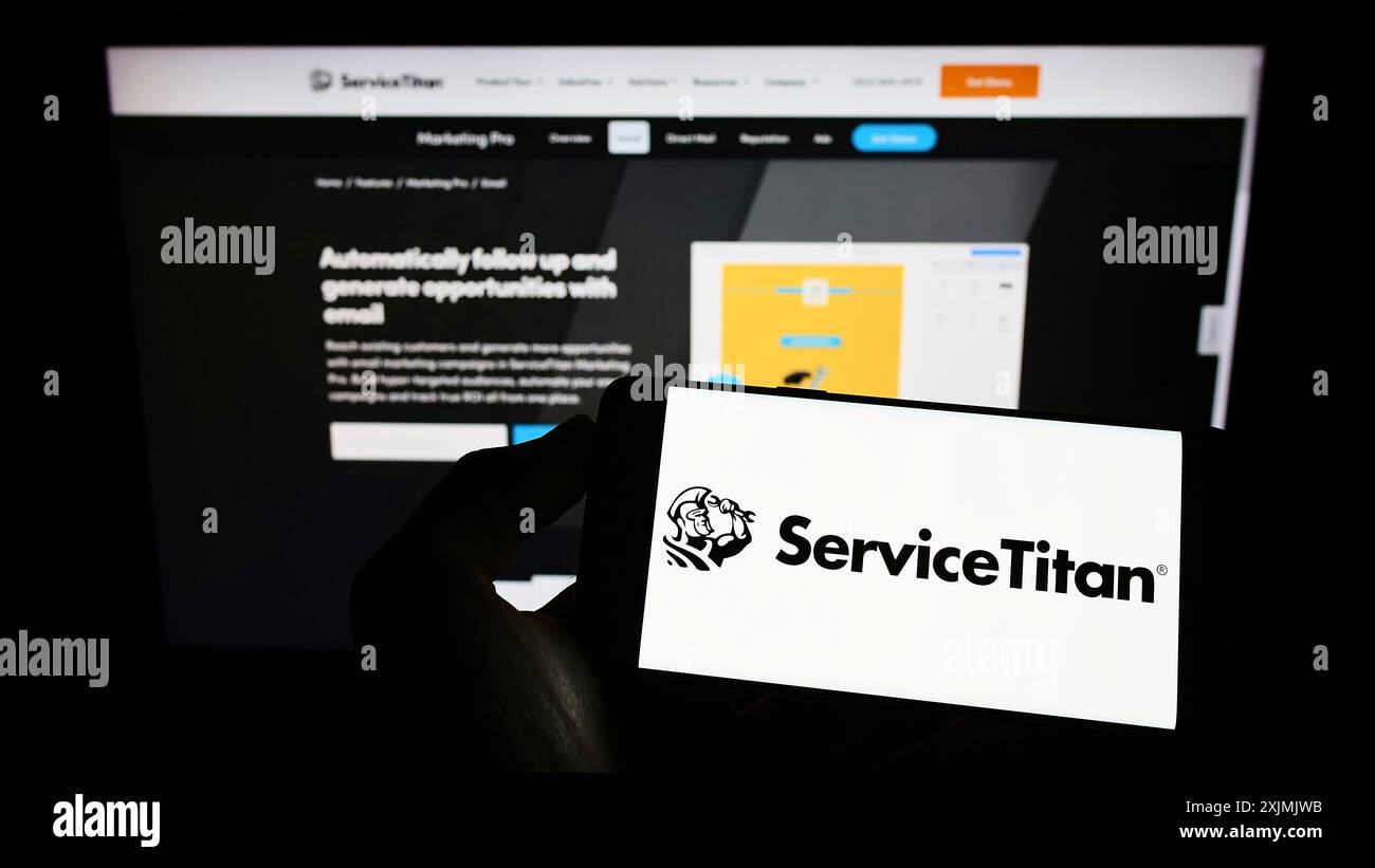 Stoccarda, Germania, 07-31-2022: Persona che possiede uno smartphone con il logo della società software statunitense ServiceTitan Inc. Sullo schermo davanti al sito Web. Concentrati su Foto Stock