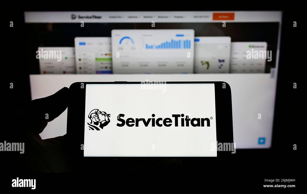 Stoccarda, Germania, 07-31-2022: Persona che detiene un telefono cellulare con il logo della società di software americana ServiceTitan Inc. Sullo schermo davanti alla pagina Web. Foto Stock