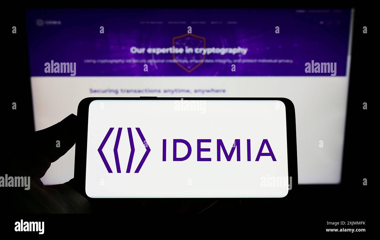 Stoccarda, Germania, 09-09-2022: Persona che detiene uno smartphone con il logo dell'azienda tecnologica IDEMIA France SAS sullo schermo davanti al sito web. Concentrati su Foto Stock