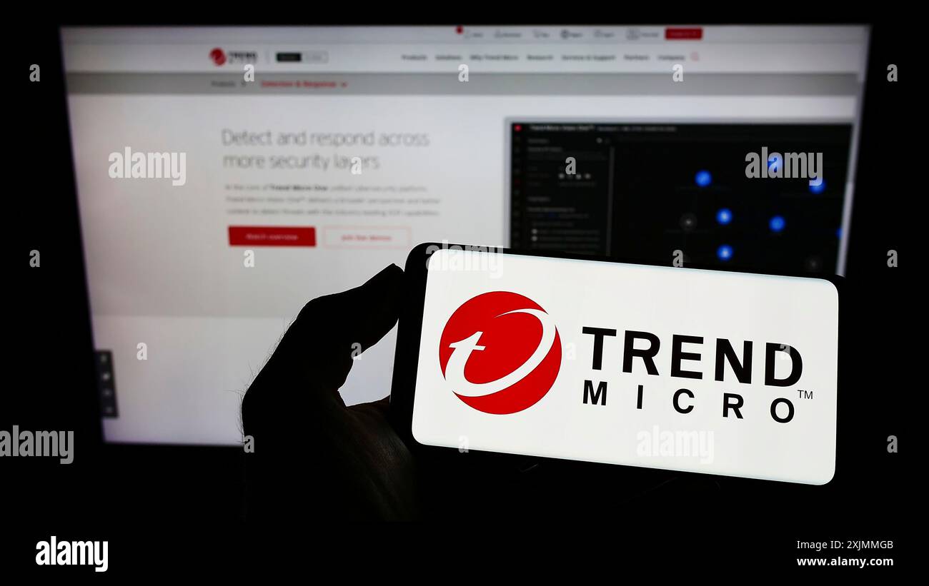 Stoccarda, Germania, 09-08-2022: Persona che detiene un telefono cellulare con il logo della società di sicurezza informatica Trend Micro Inc. Sullo schermo di fronte al Web aziendale Foto Stock