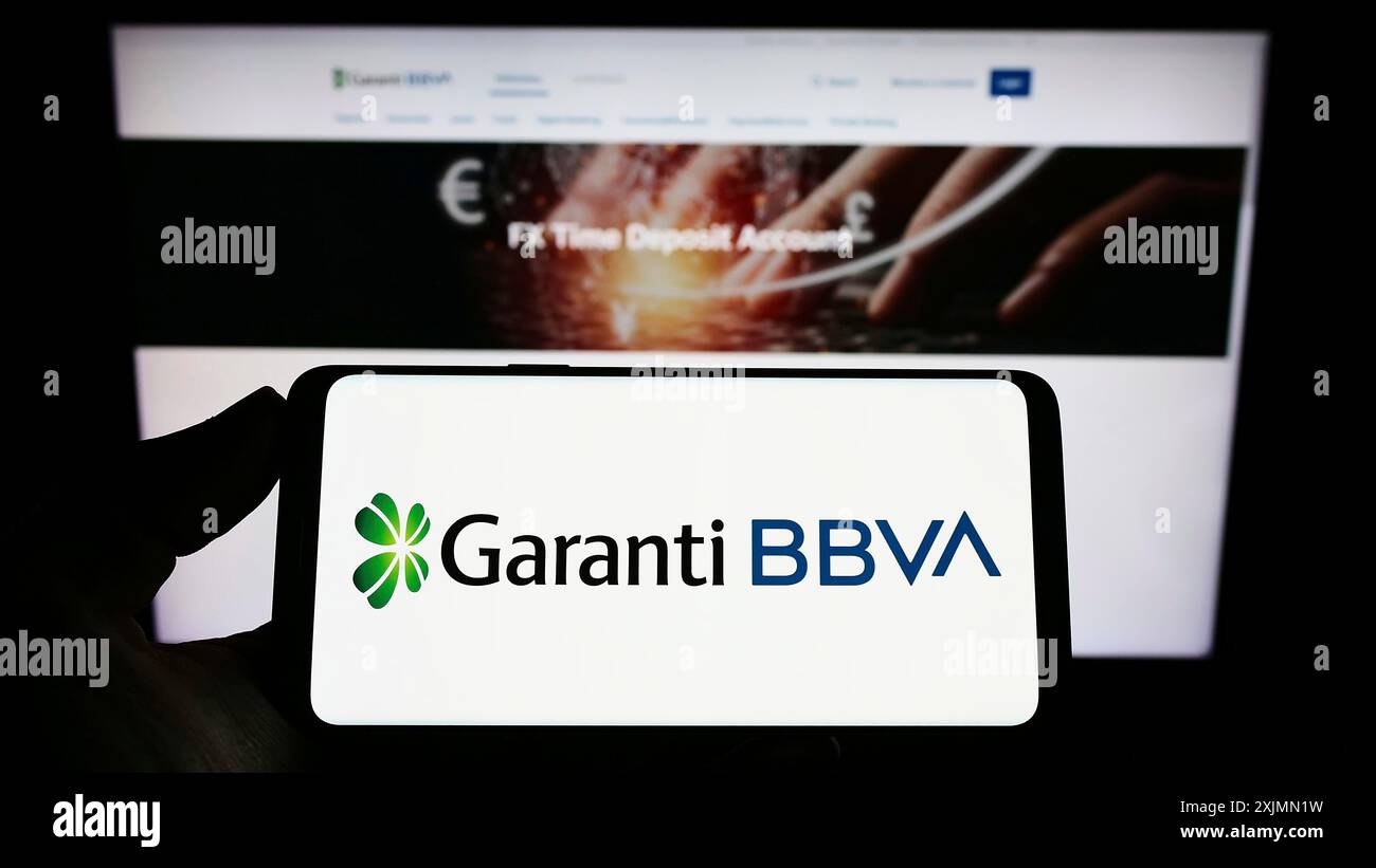 Smartphone con logo della società turca di servizi finanziari Garanti BBVA sullo schermo davanti al sito web. Mettere a fuoco il display del telefono Foto Stock