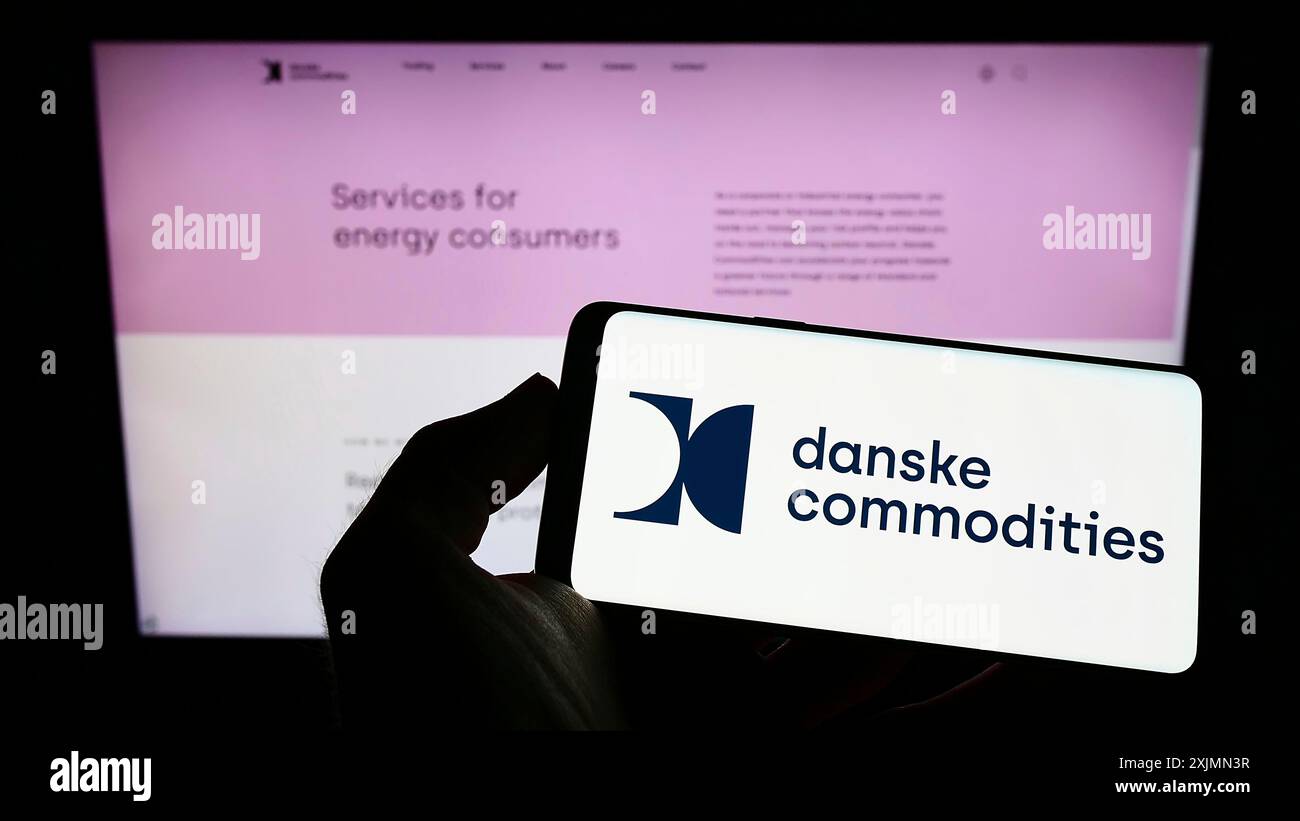 Smartphone con logo della società di commercio dell'energia Danske Commodities sullo schermo davanti al sito Web. Mettere a fuoco il display del telefono Foto Stock