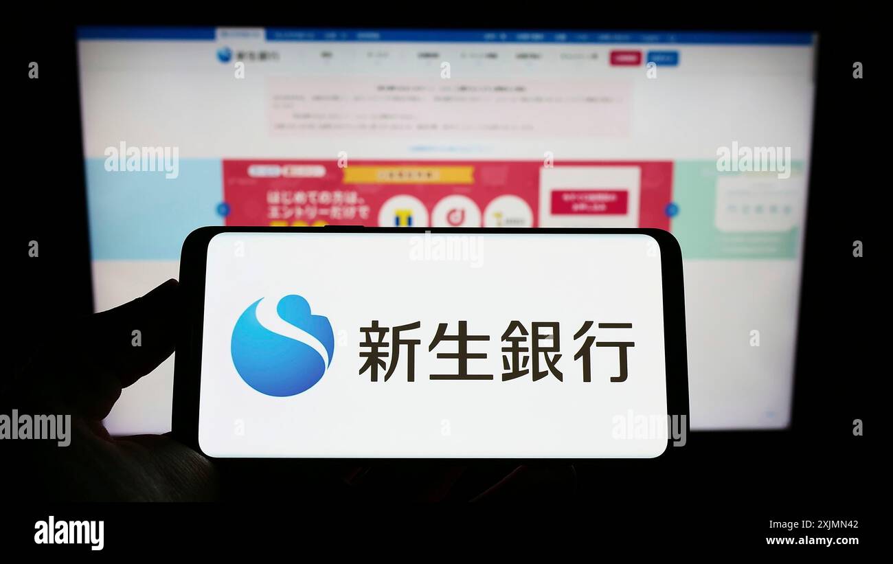 Smartphone con logo della società finanziaria giapponese Shinsei Bank Limited sullo schermo davanti al sito Web. Mettere a fuoco il display del telefono Foto Stock