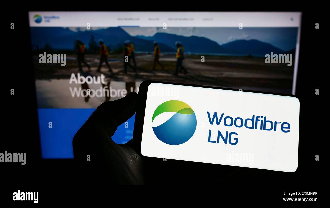 Smartphone con logo della società canadese di gas Woodfiber LNG Limited sullo schermo davanti al sito Web. Mettere a fuoco il display del telefono Foto Stock