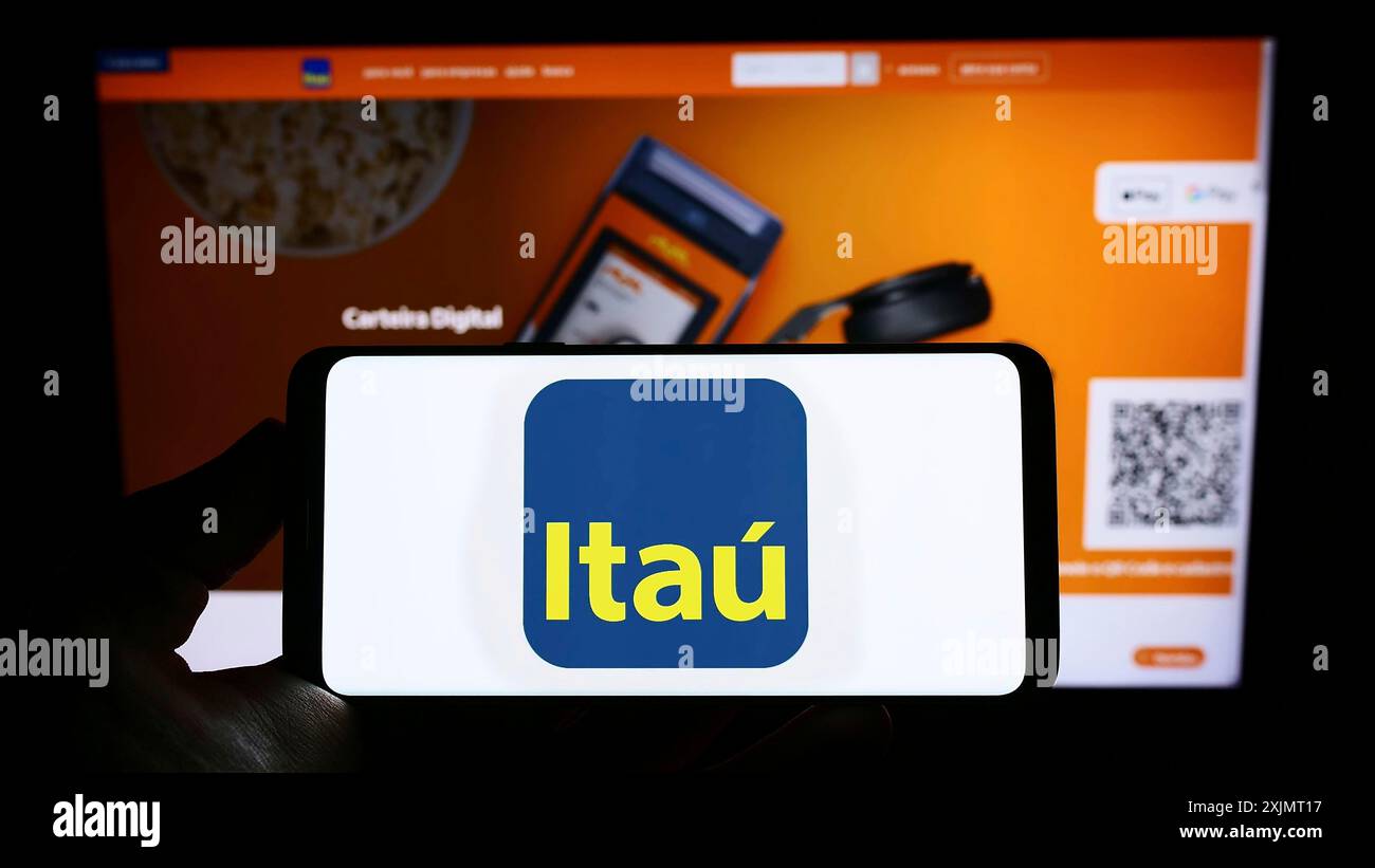 Stoccarda, Germania, 10-14-2022: Persona che detiene un telefono cellulare con logo della società brasiliana Itau Unibanco Holding SA sullo schermo di fronte alla pagina web. Foto Stock