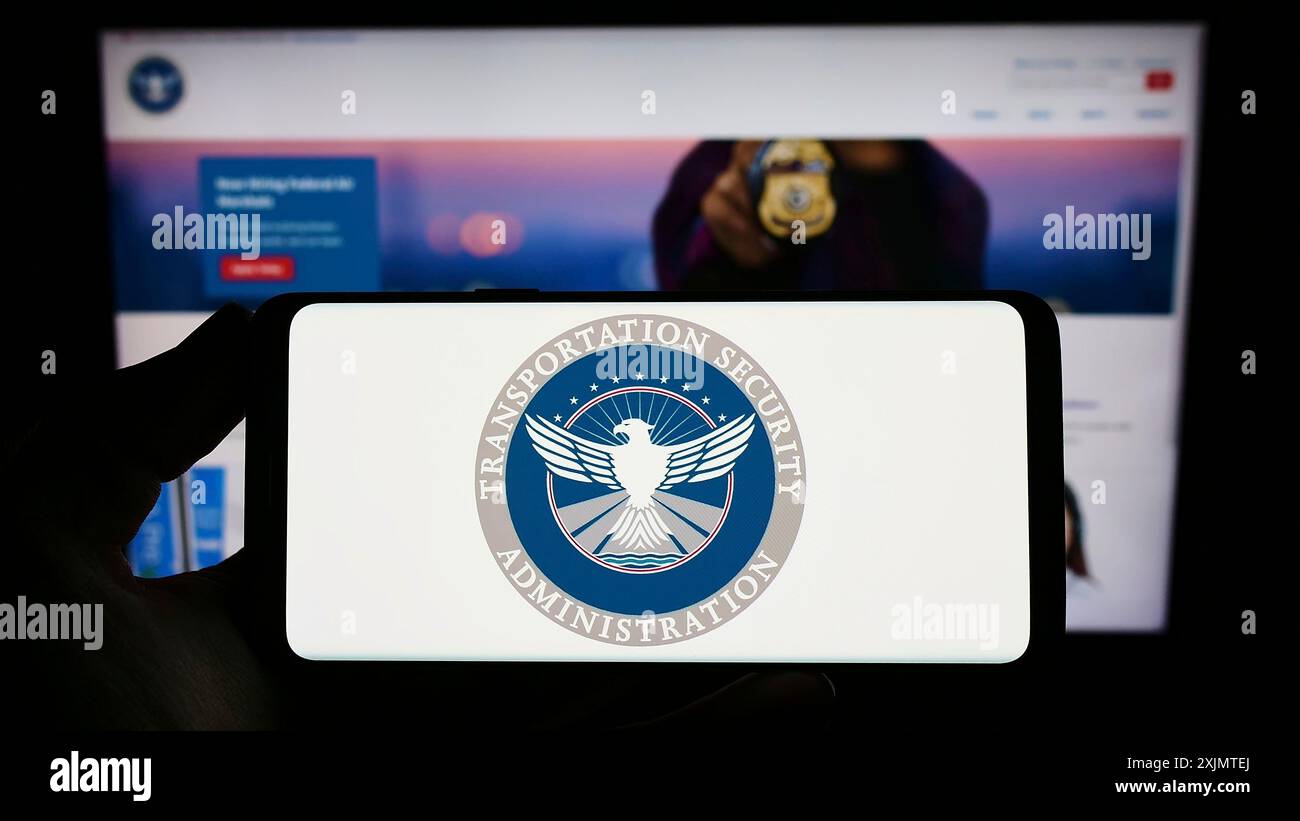 Stoccarda, Germania, 10-24-2022: Persona che possiede uno smartphone con il sigillo della Transportation Security Administration (TSA) sullo schermo di fronte al sito web. Foto Stock