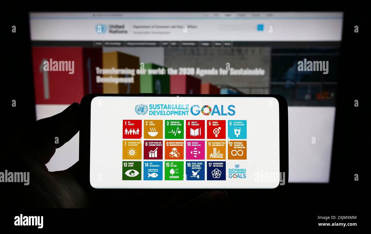 Stoccarda, Germania, 12-19-2022: Persona con smartphone e logo degli obiettivi di sviluppo sostenibile delle Nazioni Unite (SDG) sullo schermo davanti al sito web. Concentrati su Foto Stock