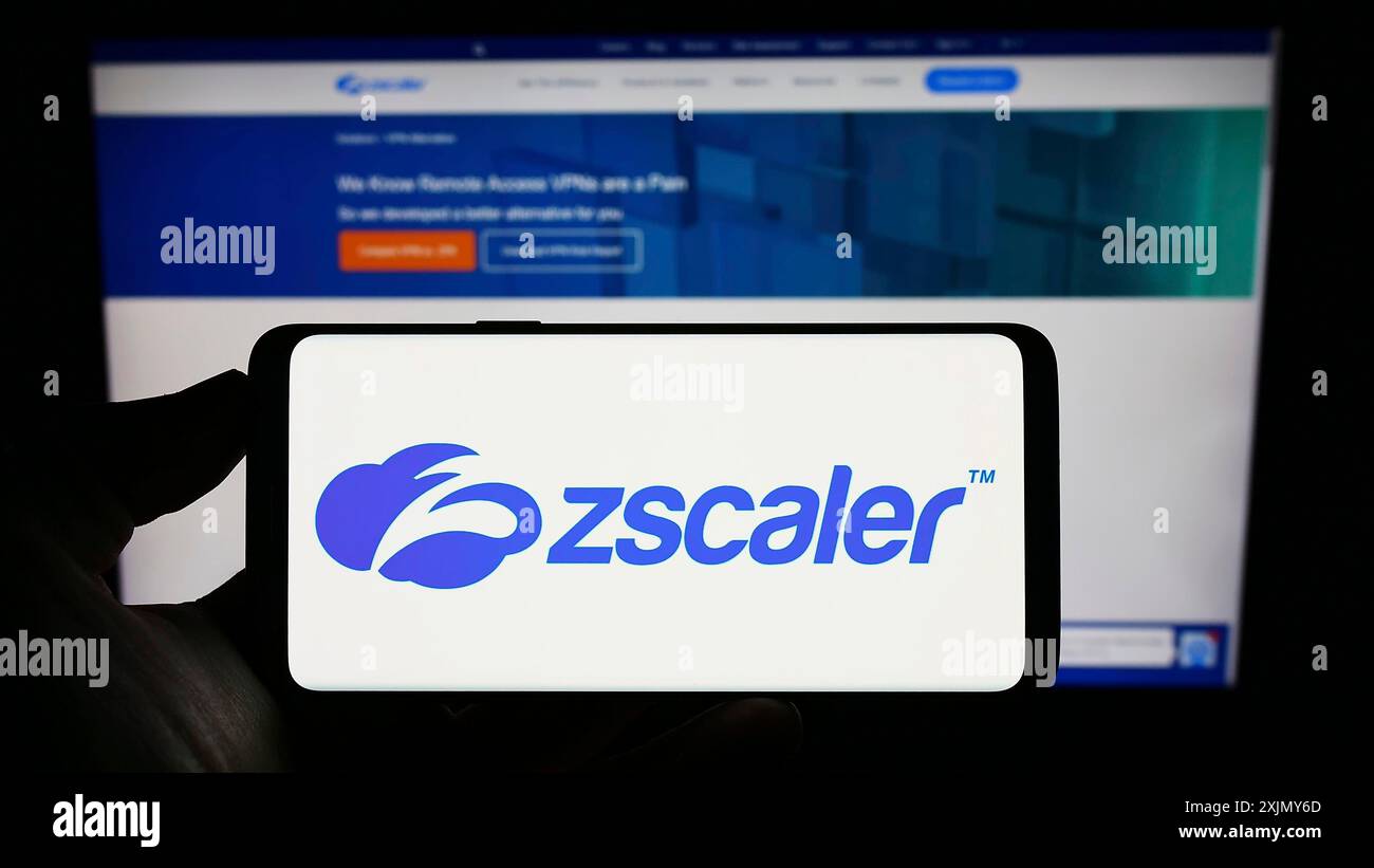 Stoccarda, Germania, 12-30-2022: Persona che detiene un cellulare con il logo della società statunitense di sicurezza sul cloud Zscaler Inc. Sullo schermo di fronte alla pagina Web aziendale. Foto Stock