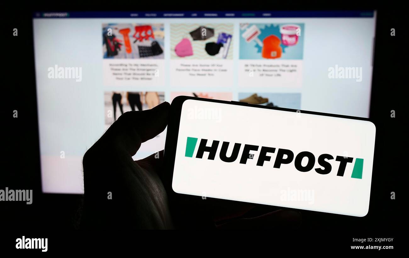 Stoccarda, Germania, 12-30-2022: Persona che tiene un telefono cellulare con il logo della società di notizie americana HuffPost sullo schermo di fronte alla pagina web aziendale. Foto Stock