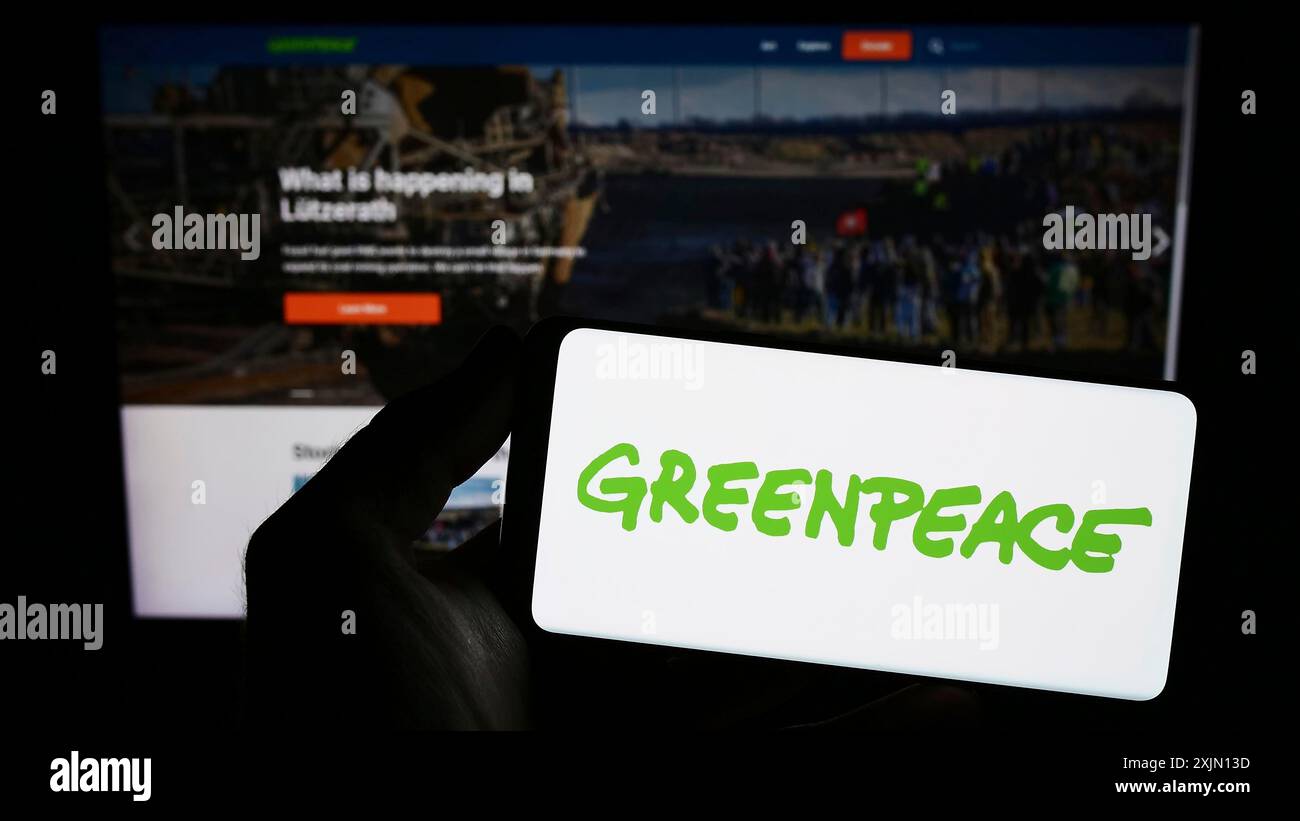 Stoccarda, Germania, 01-26-2023: Persona con smartphone con logo della rete di campagne ambientali Greenpeace sullo schermo di fronte al sito web. Foto Stock
