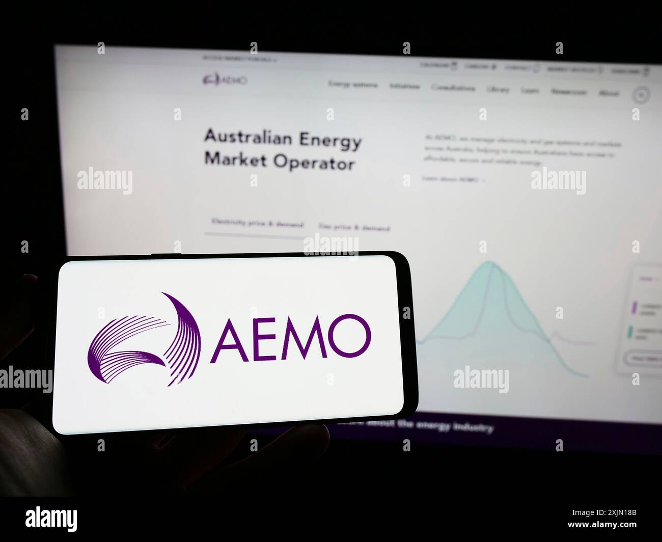 Stoccarda, Germania, 01-27-2023: Persona che detiene un telefono cellulare con il logo dell'operatore australiano del mercato dell'energia (AEMO) sullo schermo davanti al web aziendale Foto Stock