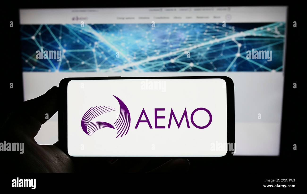 Stoccarda, Germania, 01-27-2023: Persona che tiene un cellulare con il logo dell'operatore australiano del mercato dell'energia (AEMO) sullo schermo davanti alla pagina web. Concentrati Foto Stock