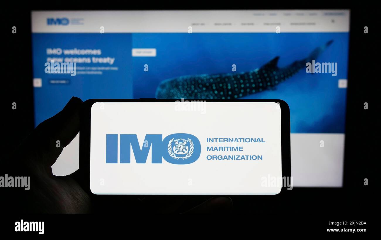 Stoccarda, Germania, 03-07-2023: Persona che possiede uno smartphone con il logo dell'Organizzazione marittima internazionale (IMO) sullo schermo davanti al sito web. Concentrati Foto Stock