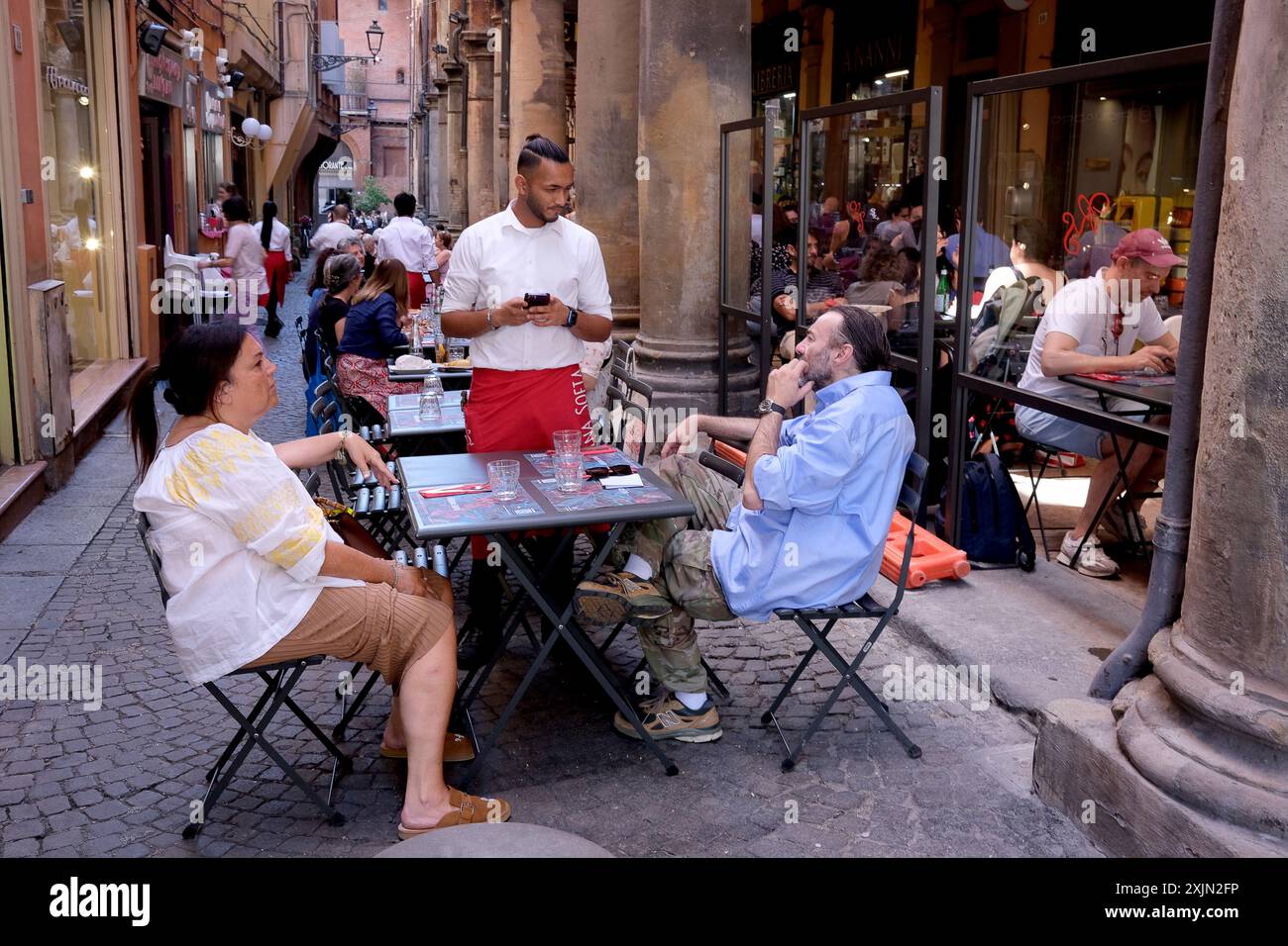Bologna, Italia. Il cameriere prende le ordinazioni di cibo fuori dal ristorante nella strada laterale Foto Stock