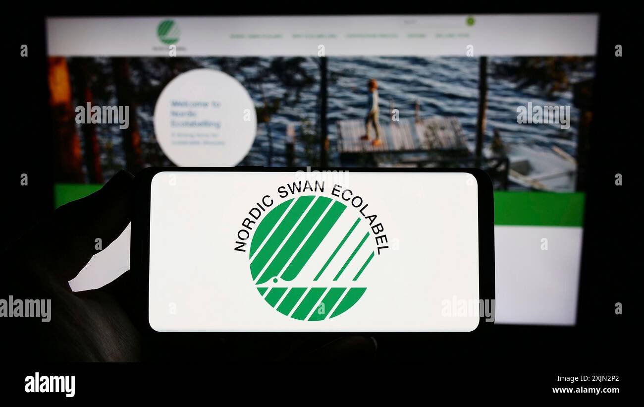 Stoccarda, Germania, 03-11-2023: Persona in possesso di smartphone con logo di certificazione ambientale Nordic Ecolabel sullo schermo di fronte al sito web. Foto Stock