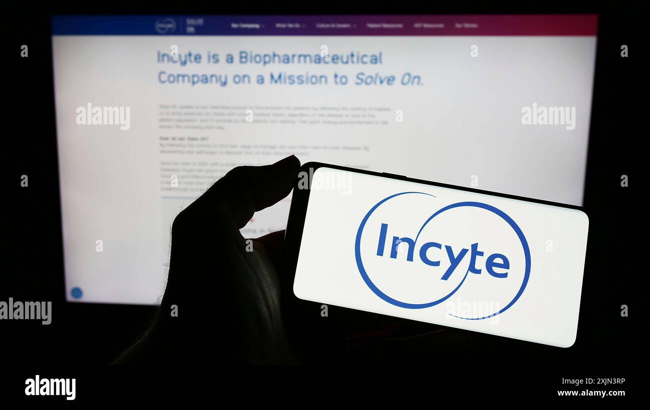 Stoccarda, Germania, 03-22-2023: Persona che possiede uno smartphone con il logo della società farmaceutica statunitense Incyte Corporation sullo schermo davanti al sito web. Foto Stock