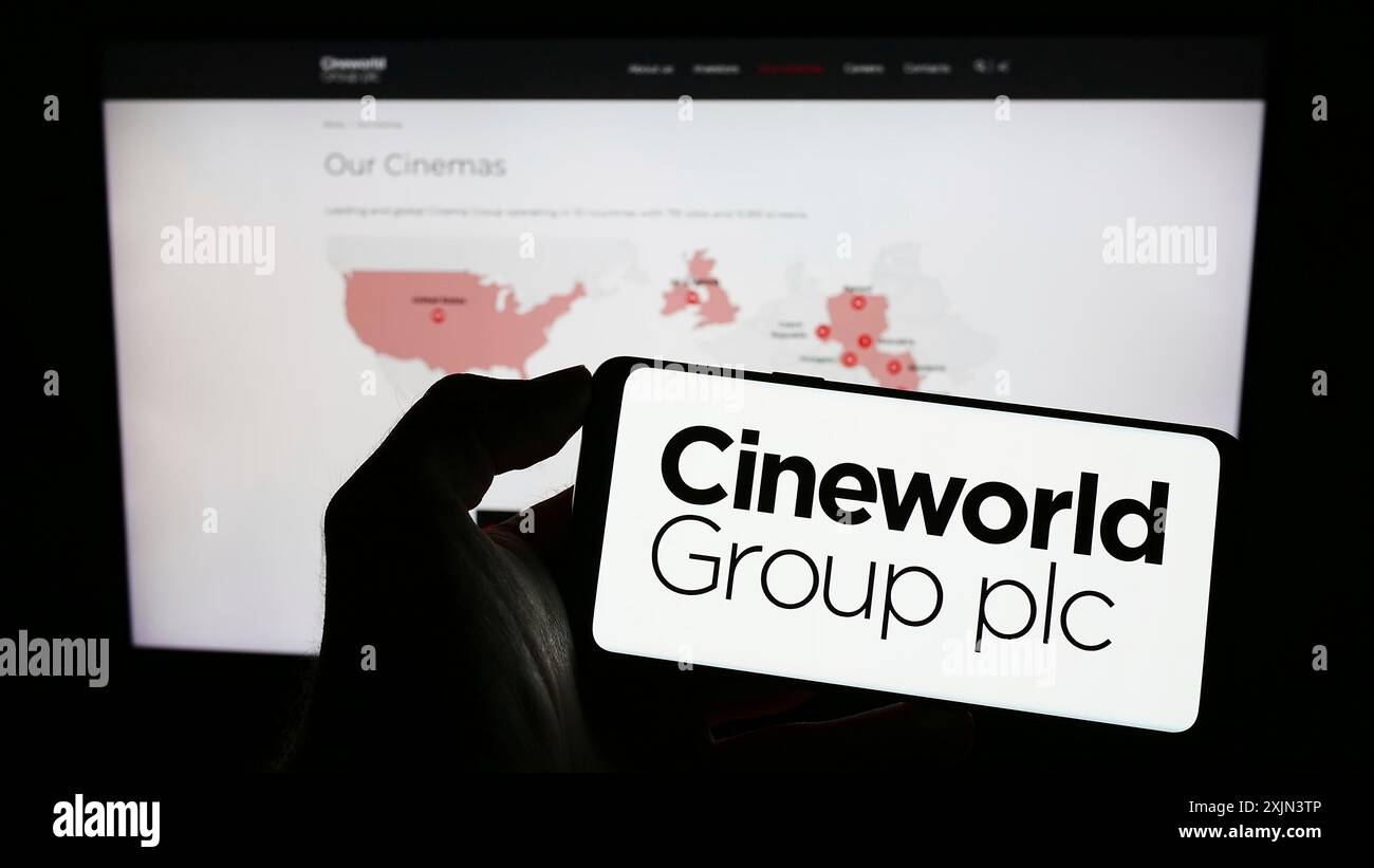 Stoccarda, Germania, 03-19-2023: Persona che possiede uno smartphone con il logo della società cinematografica britannica Cineworld Group plc sullo schermo davanti al sito web. Foto Stock