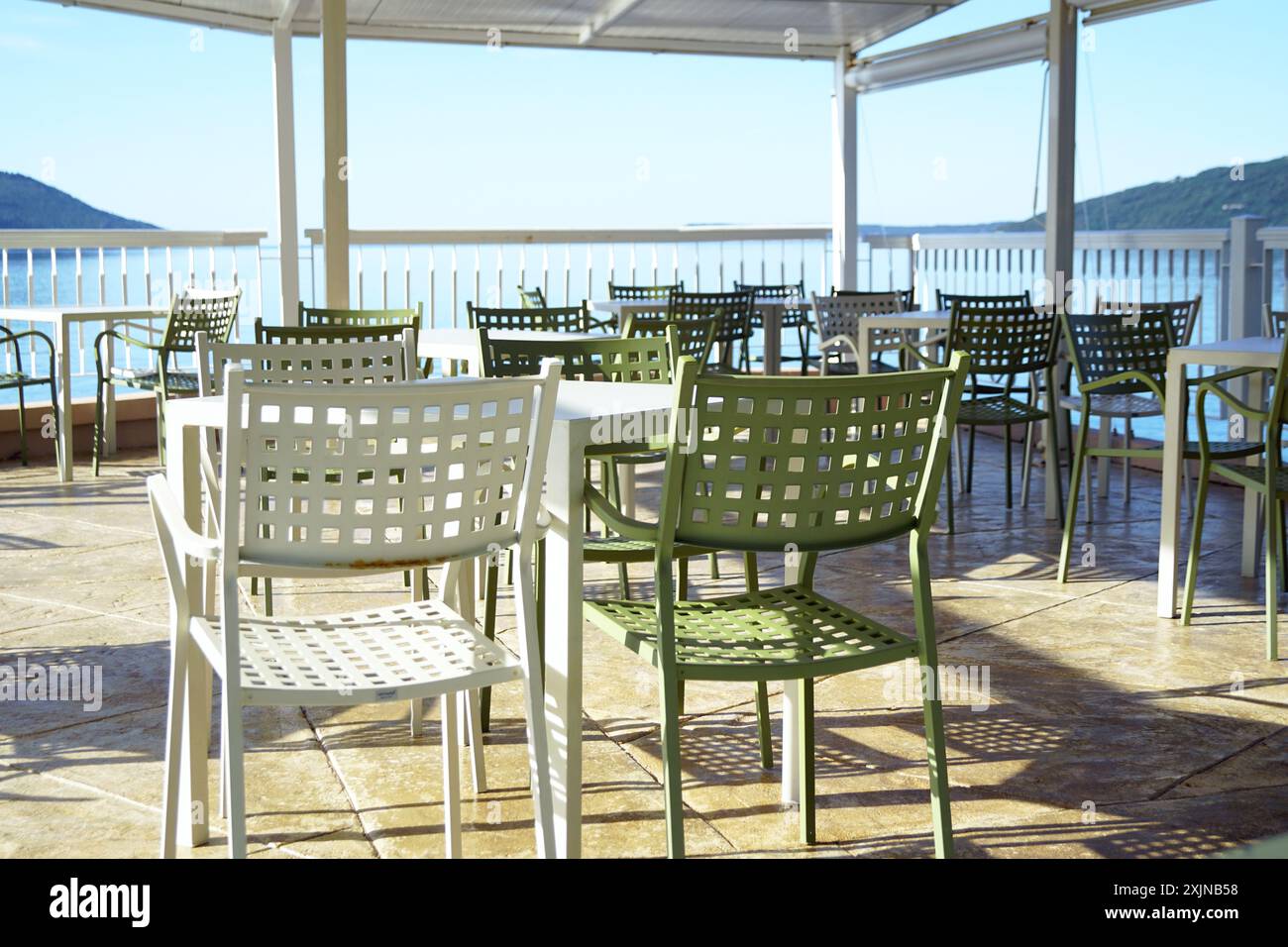 Piccola impresa sulla costa del Montenegro: Un caffè aperto senza persone. Tavoli vuoti e sedie libere in piedi sulla terrazza con vista sul mare. Foto Stock