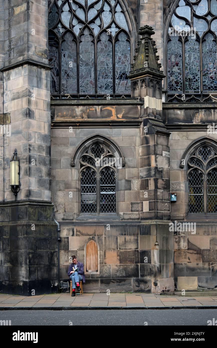 Giovane seduto a leggere in Parliament Square nella città vecchia di Edimburgo. Foto Stock