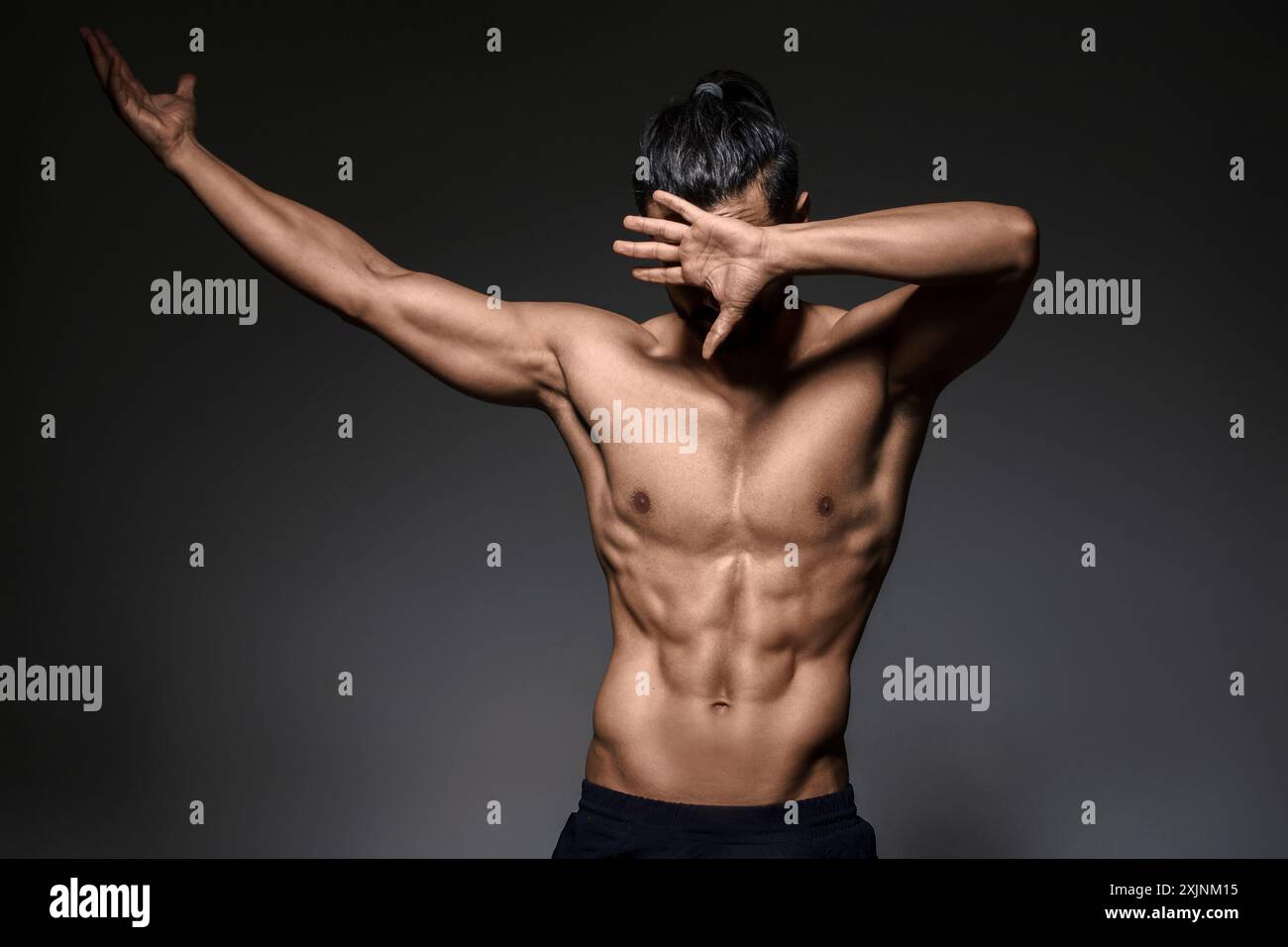 Uomo muscoloso che posa con il braccio sollevato, mostrando fitness e forza. Foto Stock