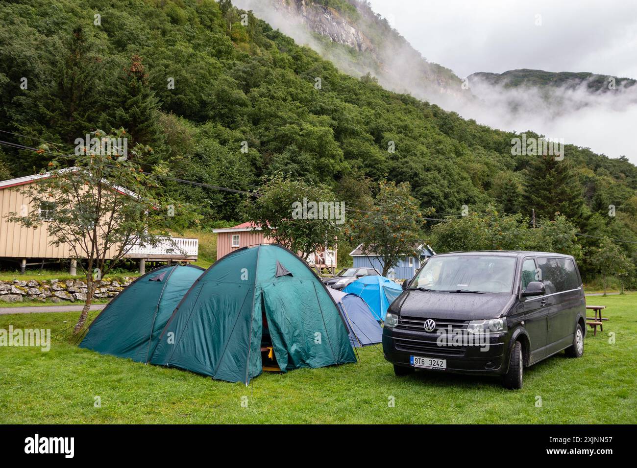 KINSARVIK, NORVEGIA - 13 AGOSTO 2016: Auto Volkswagen Caravelle nel campo Kinsarvik in Norvegia, clima nuvoloso e tende bagnate Foto Stock