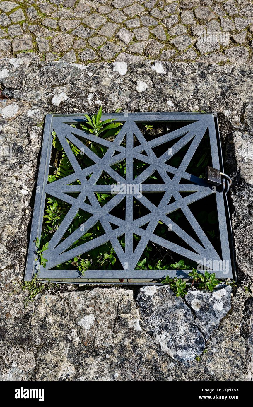 Intricata griglia metallica con un design a stella sul sentiero in pietra del castello moresco di Sintra Foto Stock