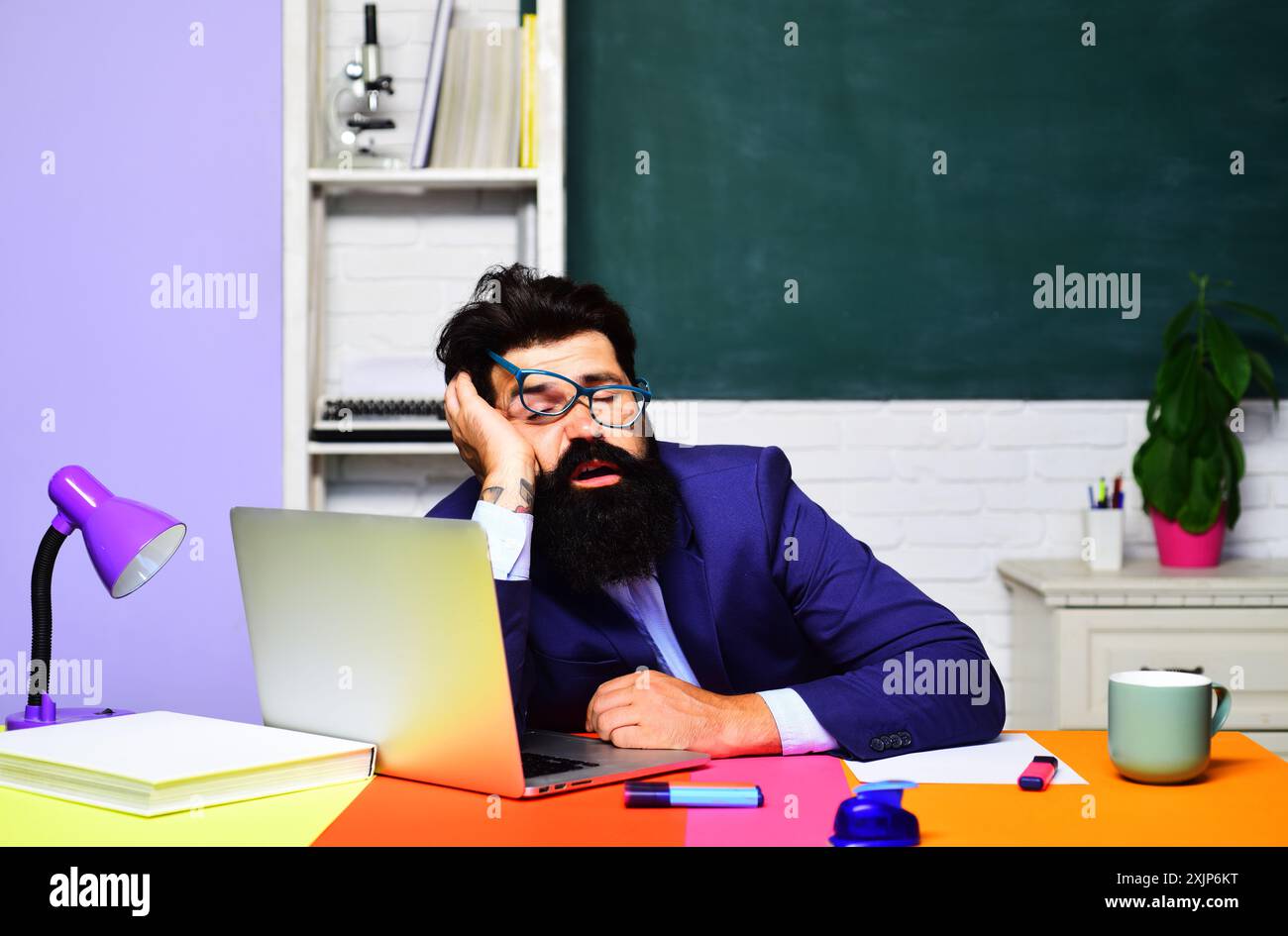 Insegnante stanca che dorme dopo una lezione in classe. Pausa scolastica. Stanco insegnante di scuola maschile che dorme sulla scrivania. Studente universitario sovraccarico di lavoro Foto Stock