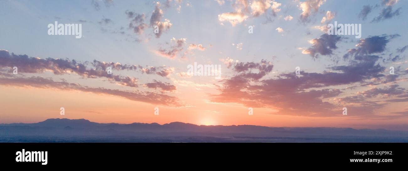 Il paesaggio montano all'alba è impreziosito da nuvole colorate che creano un'alba mozzafiato Foto Stock
