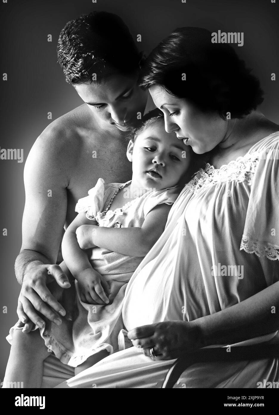Bianco e nero Ritratto di una donna incinta seduta con suo marito e sua figlia. Foto Stock