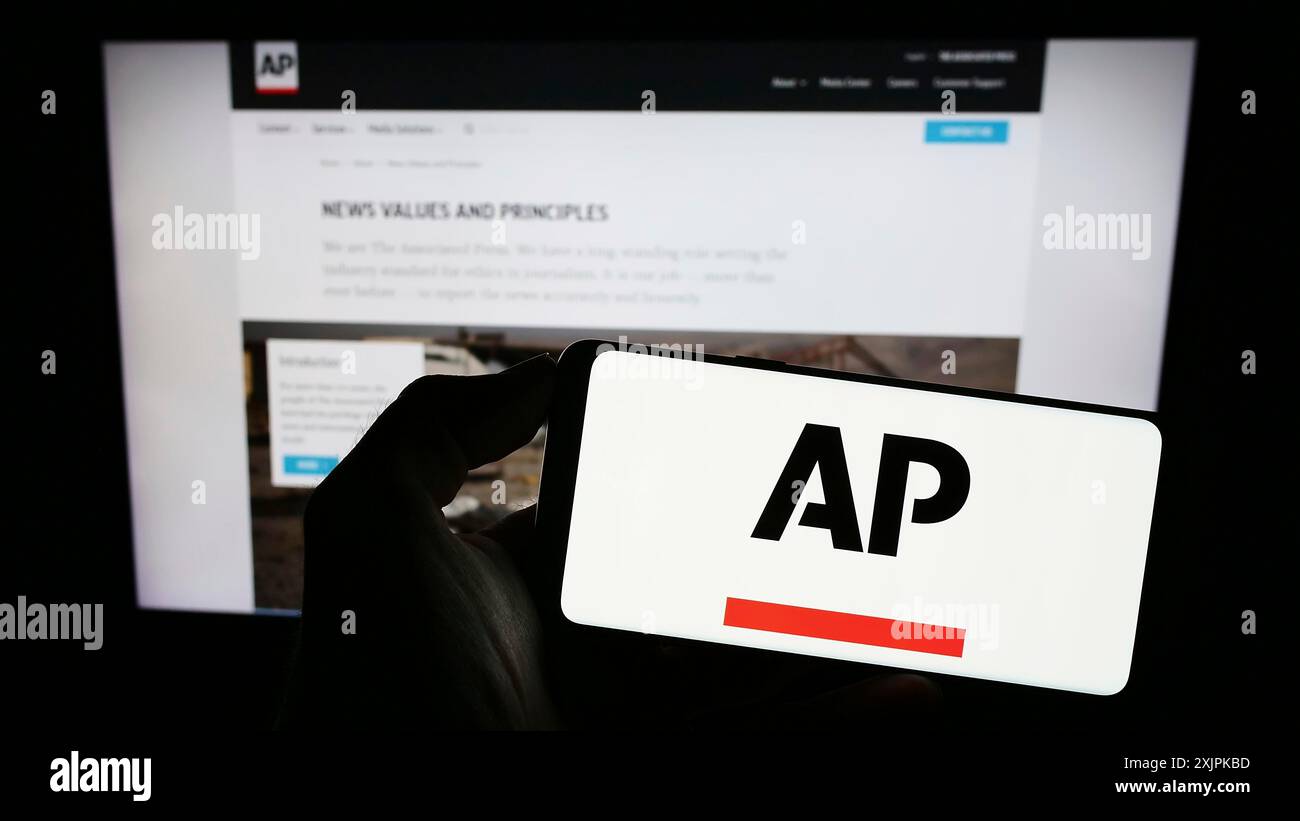 Stoccarda, Germania, 07-11-2023: Persona che possiede un telefono cellulare con il logo dell'agenzia di stampa americana Associated Press (AP) sullo schermo davanti alla pagina web. Foto Stock