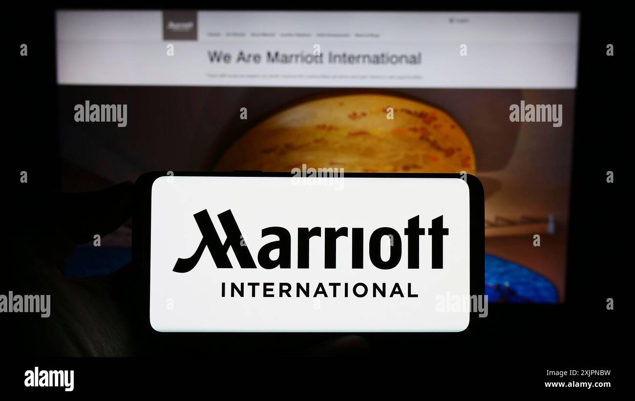 Stoccarda, Germania, 08-04-2023: Persona con smartphone con logo della società alberghiera statunitense Marriott International Inc. Sullo schermo davanti al sito Web. Foto Stock