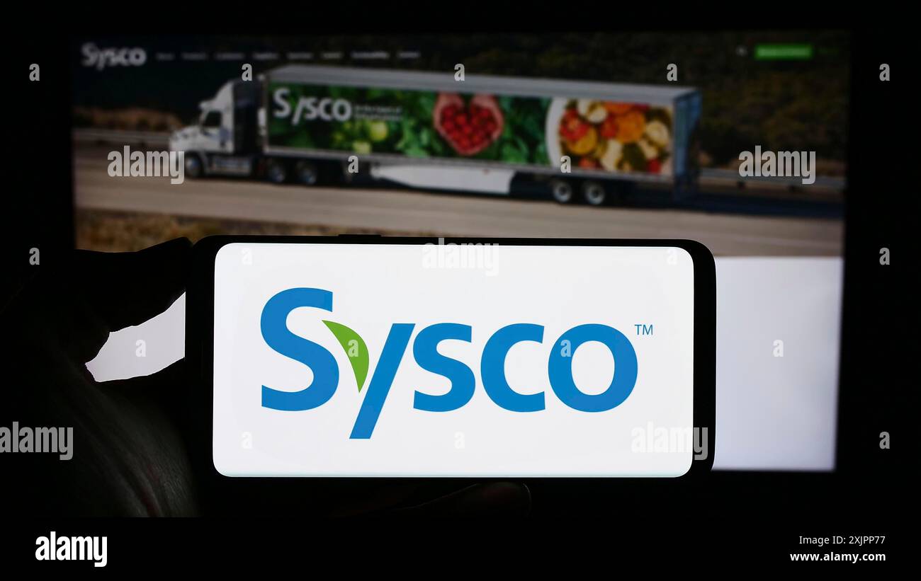 Stoccarda, Germania, 08-09-2023: Persona che detiene uno smartphone con il logo della società all'ingrosso statunitense Sysco Corporation sullo schermo di fronte al sito web. Concentrati su Foto Stock