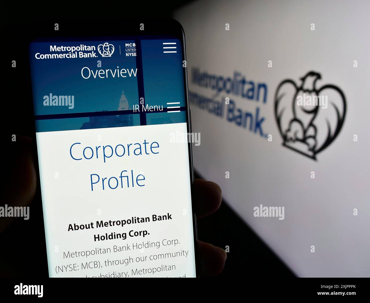Stoccarda, Germania, 11-07-2023: Persona che detiene il cellulare con pagina web della società finanziaria statunitense Metropolitan Commercial Bank (MCB) con logo. Concentrati su Foto Stock