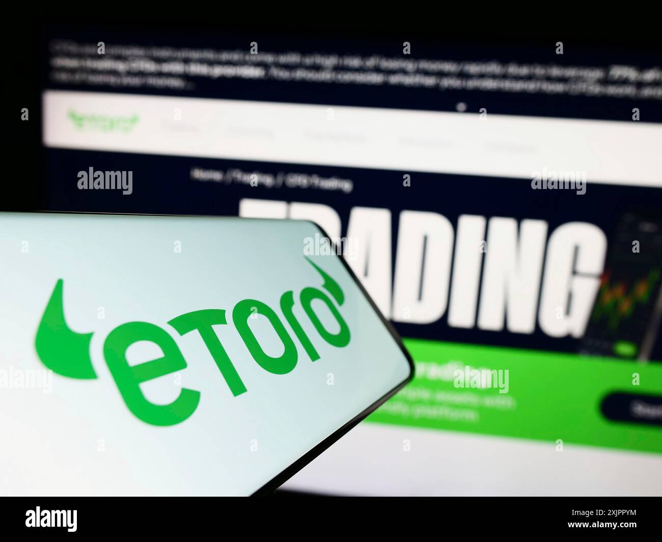 Stoccarda, Germania, 06-17-2023: Smartphone con logo della società di social trading israeliana eToro sullo schermo di fronte al sito web aziendale. Concentrati sul centro o Foto Stock