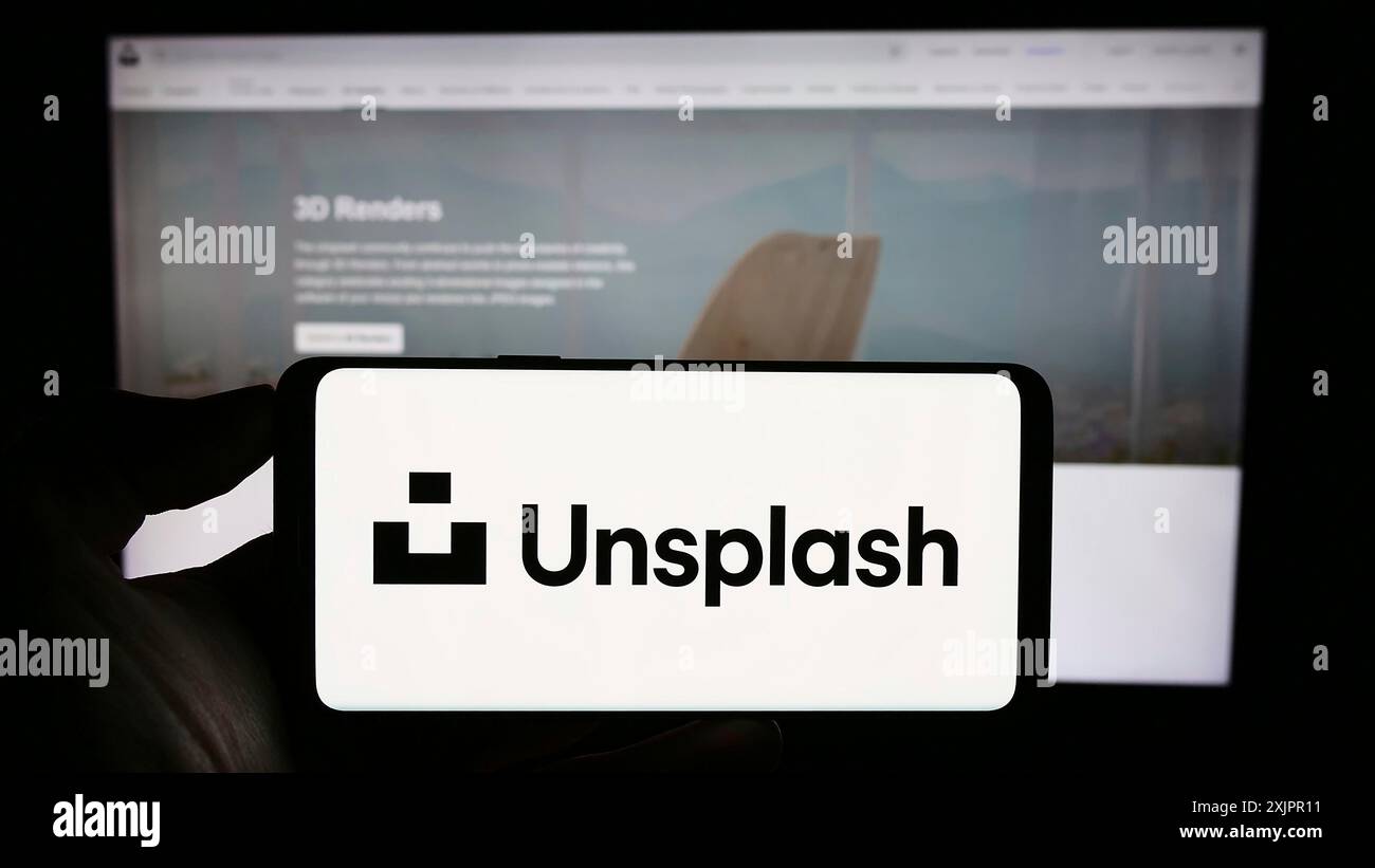 Stoccarda, Germania, 08-18-2023: Persona che detiene il cellulare con il logo della società di fotografia azionaria Unsplash Inc. Sullo schermo di fronte alla pagina web aziendale. Foto Stock