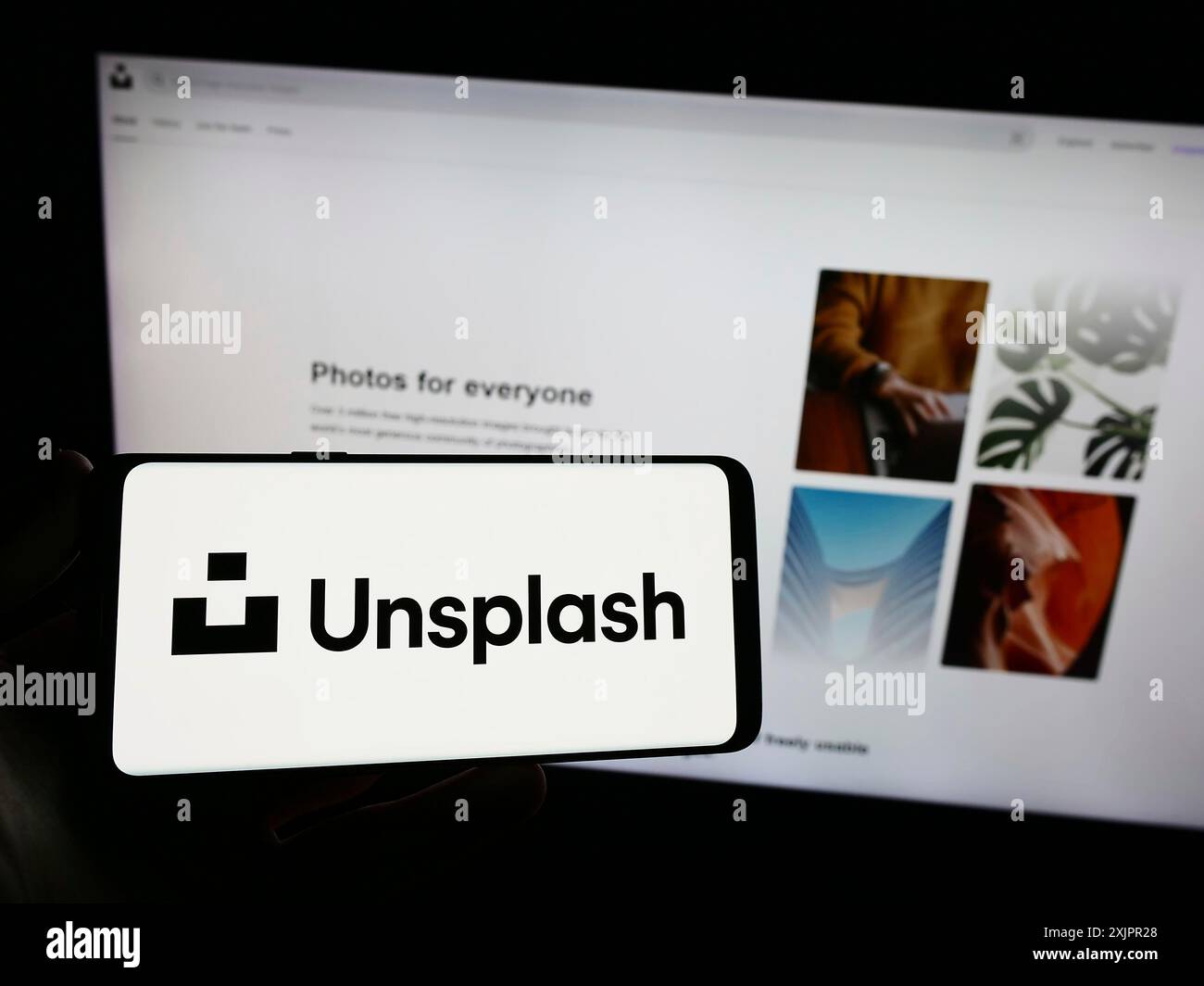 Stoccarda, Germania, 18-08-2023: Persona con smartphone con logo della società di fotografia azionaria Unsplash Inc. Sullo schermo davanti al sito web. Concentrati Foto Stock