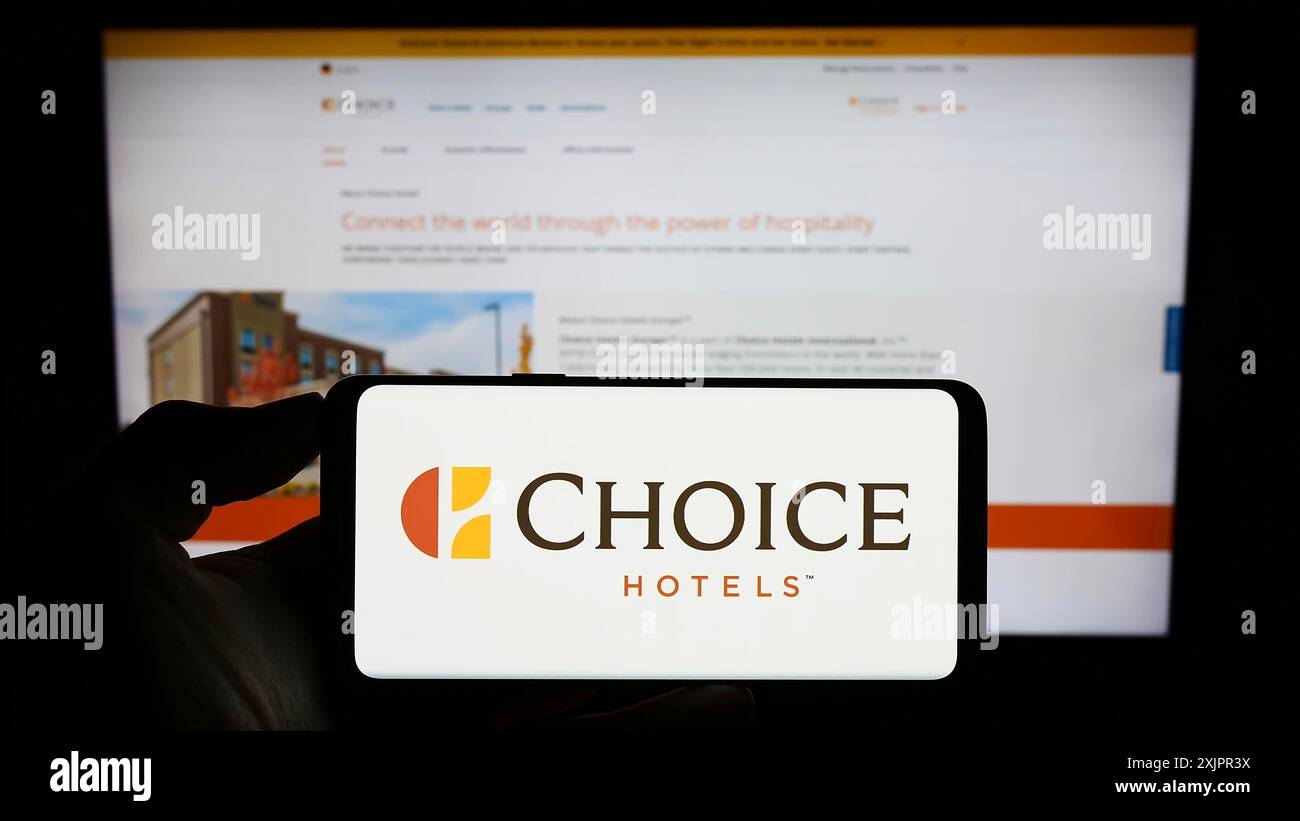 Stoccarda, Germania, 08-18-2023: Persona che detiene un cellulare con il logo della società statunitense Choice Hotels International Inc. Sullo schermo davanti all'azienda Foto Stock