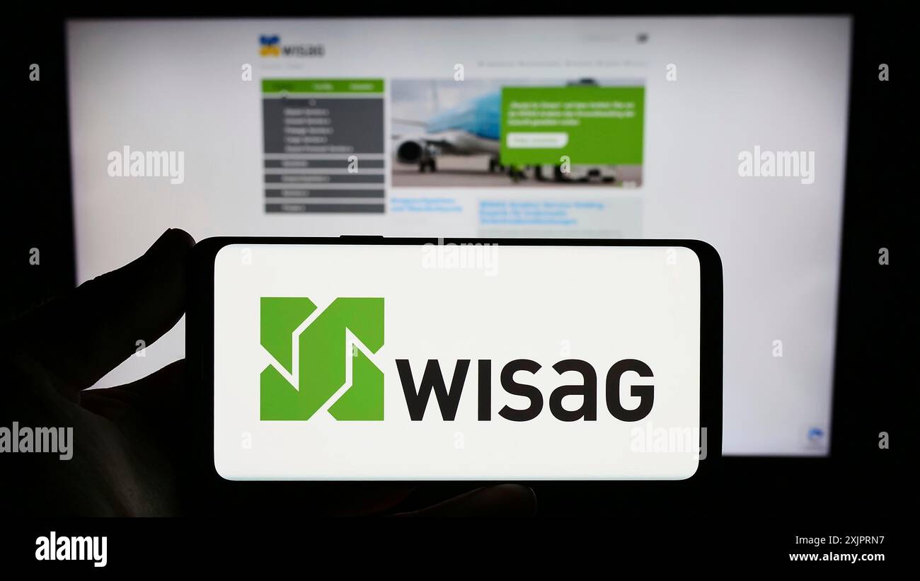 Stoccarda, Germania, 08-28-2023: Persona che detiene uno smartphone con logo della società tedesca WISAG Dienstleistungsholding se sullo schermo di fronte al sito web. Foto Stock