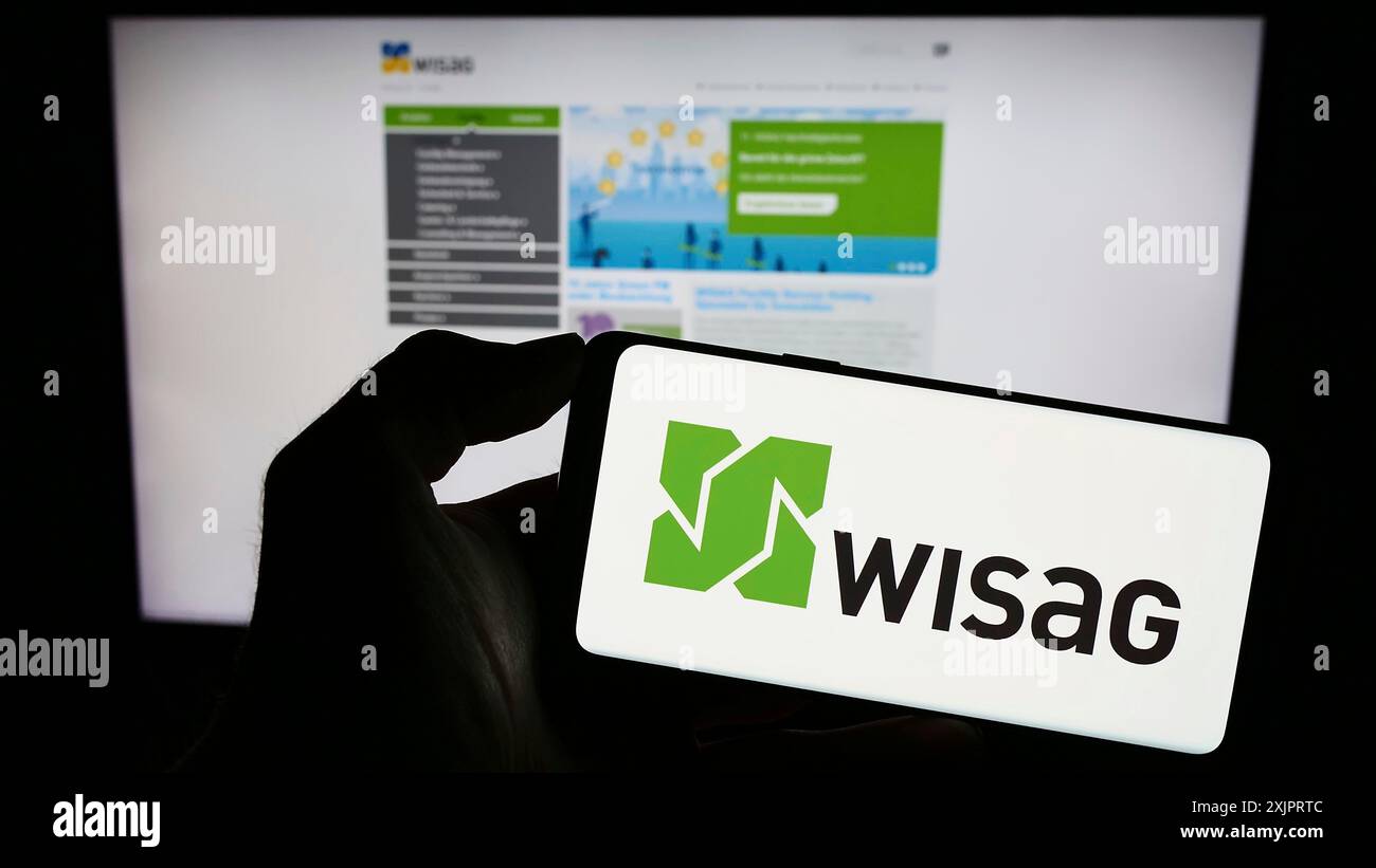 Stoccarda, Germania, 08-28-2023: Persona che detiene il cellulare con il logo della società tedesca WISAG Dienstleistungsholding se sullo schermo di fronte alla pagina web. Foto Stock