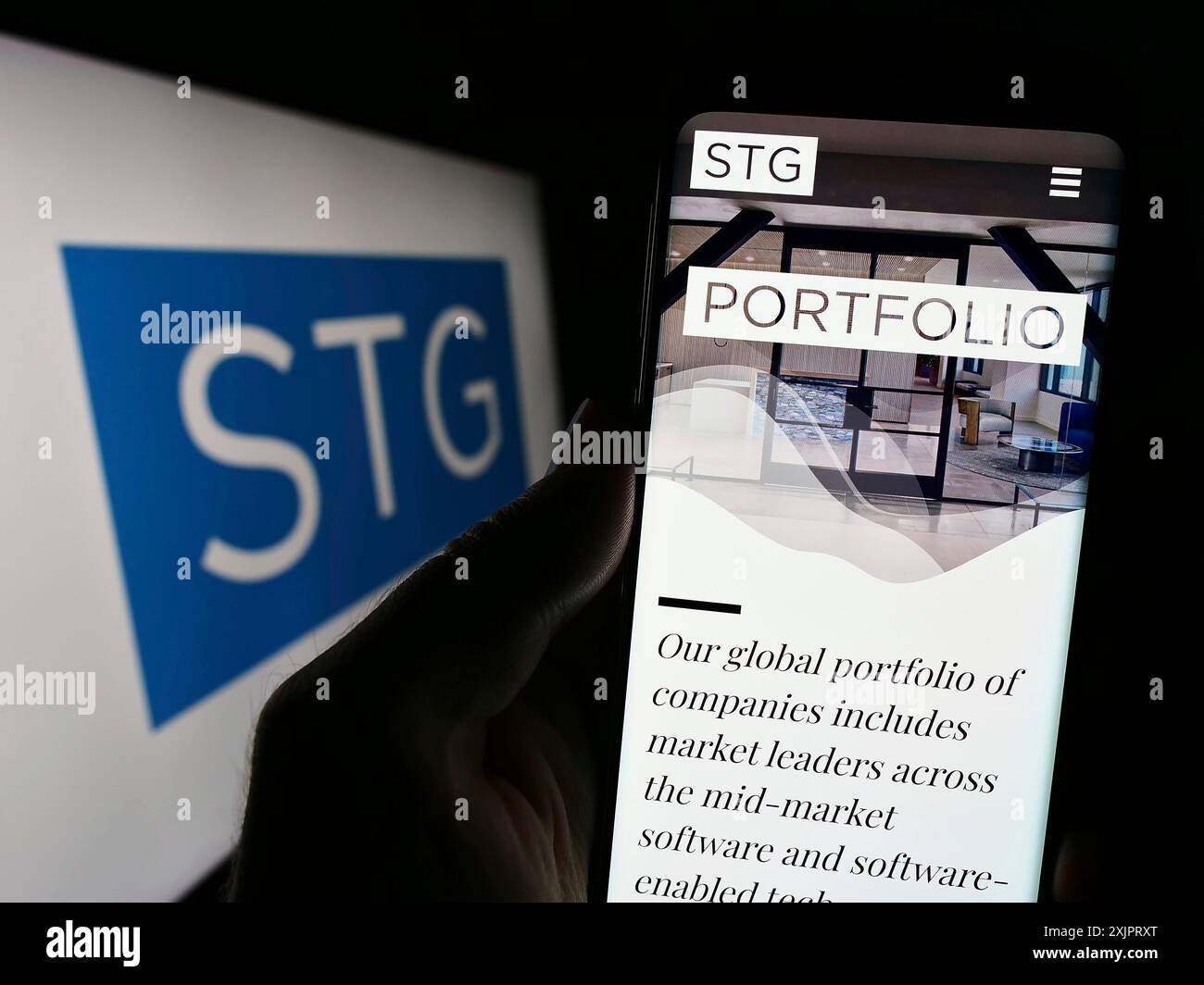 Stoccarda, Germania, 08-28-2023: Persona che detiene il cellulare con il sito web della società di private equity statunitense STG Partners LLC sullo schermo davanti al logo. Concentrati Foto Stock