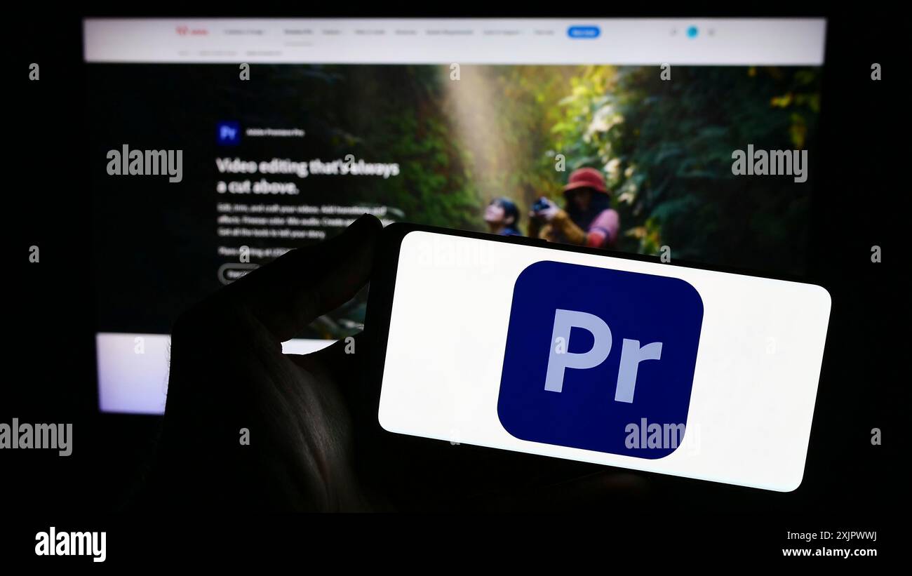 Stoccarda, Germania, 09-23-2023: Persona con smartphone con logo del software di editing video Adobe Premiere Pro sullo schermo davanti al sito Web. Concentrati Foto Stock