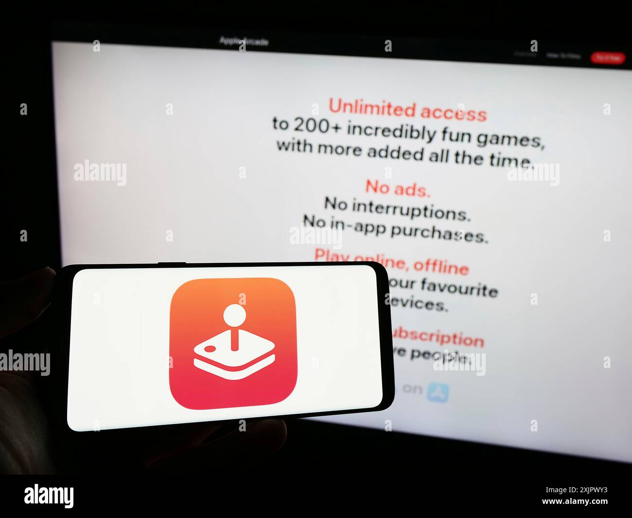 Stoccarda, Germania, 09-23-2023: Persona che tiene un telefono cellulare con il logo della piattaforma di videogiochi Apple Arcade sullo schermo di fronte alla pagina web dell'azienda. Foto Stock